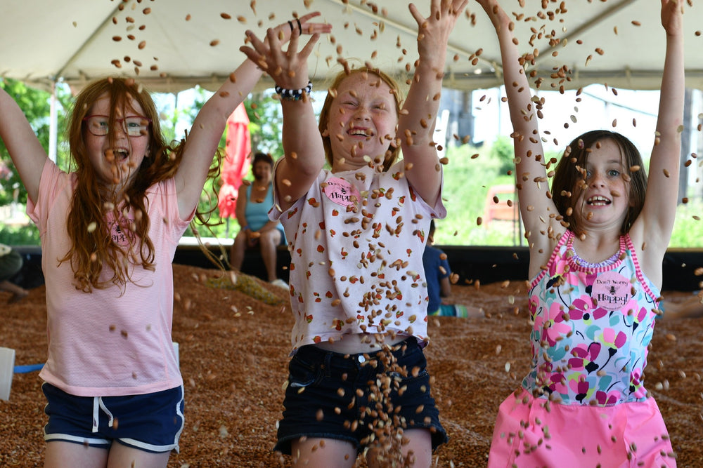 Three young girls laughing and tossing beans in the air at Clovermead Adventure Farm’s Bean Pit Attraction | Family Fun Near London Ontario | Things to do with kids 