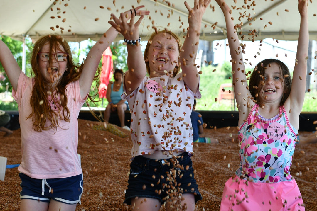 Three young girls laughing and tossing beans in the air at Clovermead Adventure Farm’s Bean Pit Attraction | Family Fun Near London Ontario | Things to do with kids 