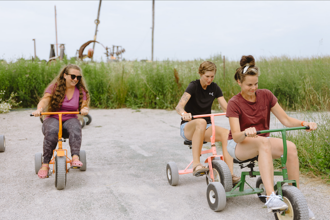 Three women riding adult-sized pedal carts and laughing at Clovermead Adventure Farm’s outdoor track | Fun for all ages 